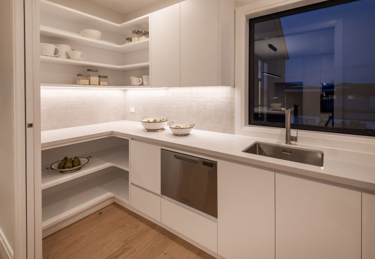 A sleek modern butler's pantry and scullery renovation completed by Level Plumbing Howick. The space features an undermount stainless steel sink with a contemporary chrome mixer tap, an integrated stainless steel dishwasher, white benchtops, open corner s