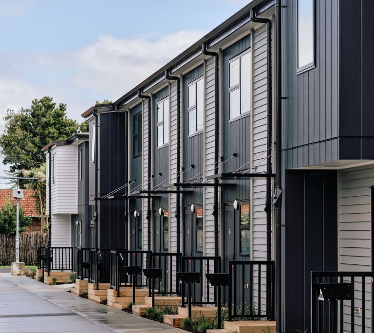Exterior drainage systems and downpipe installations along a multi-unit housing development in Howick