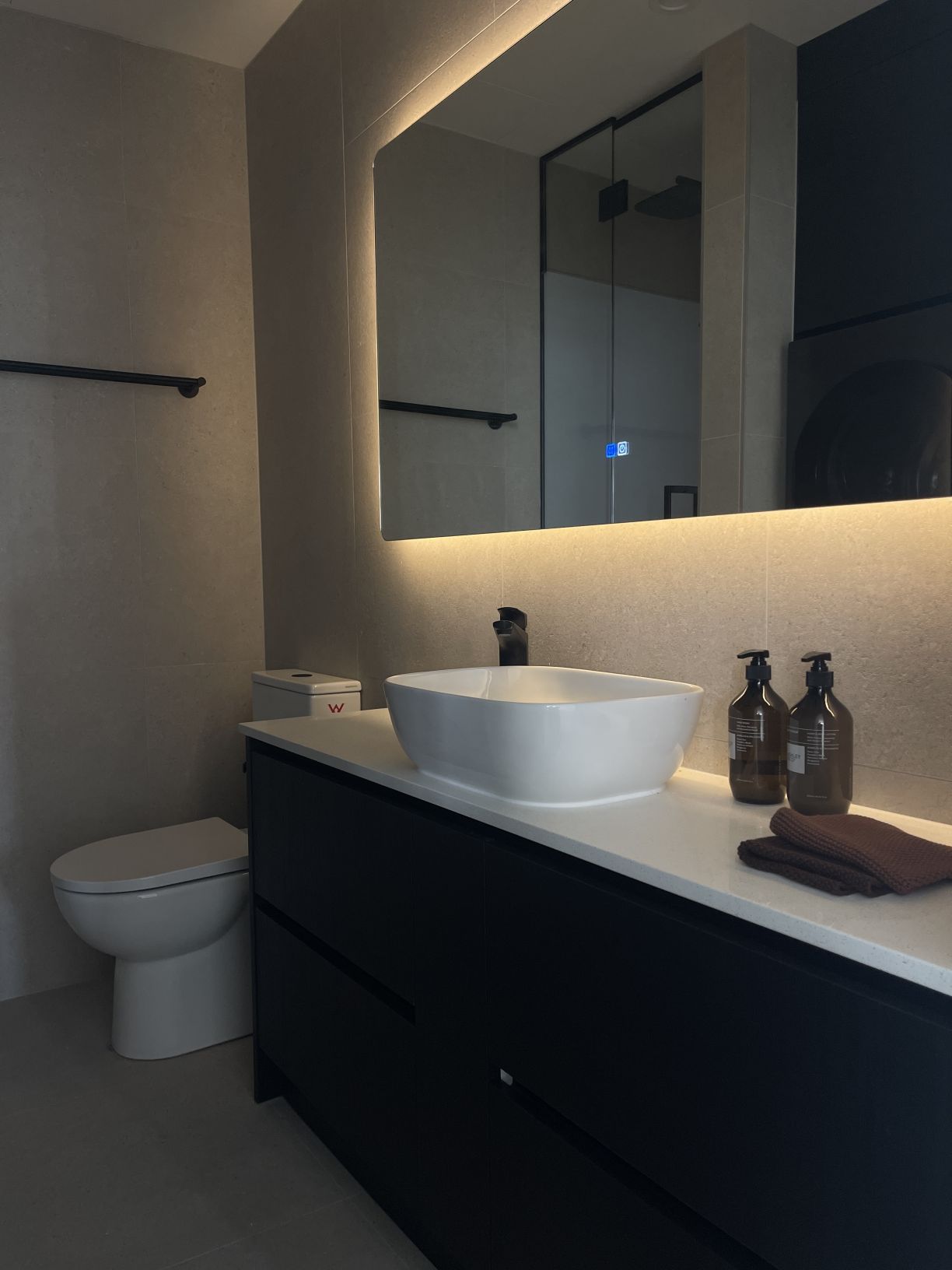 Black floating bathroom vanity unit with a white vessel basin, black mixer tap, and back-lit LED mirror installed by Level Plumbing Howick.