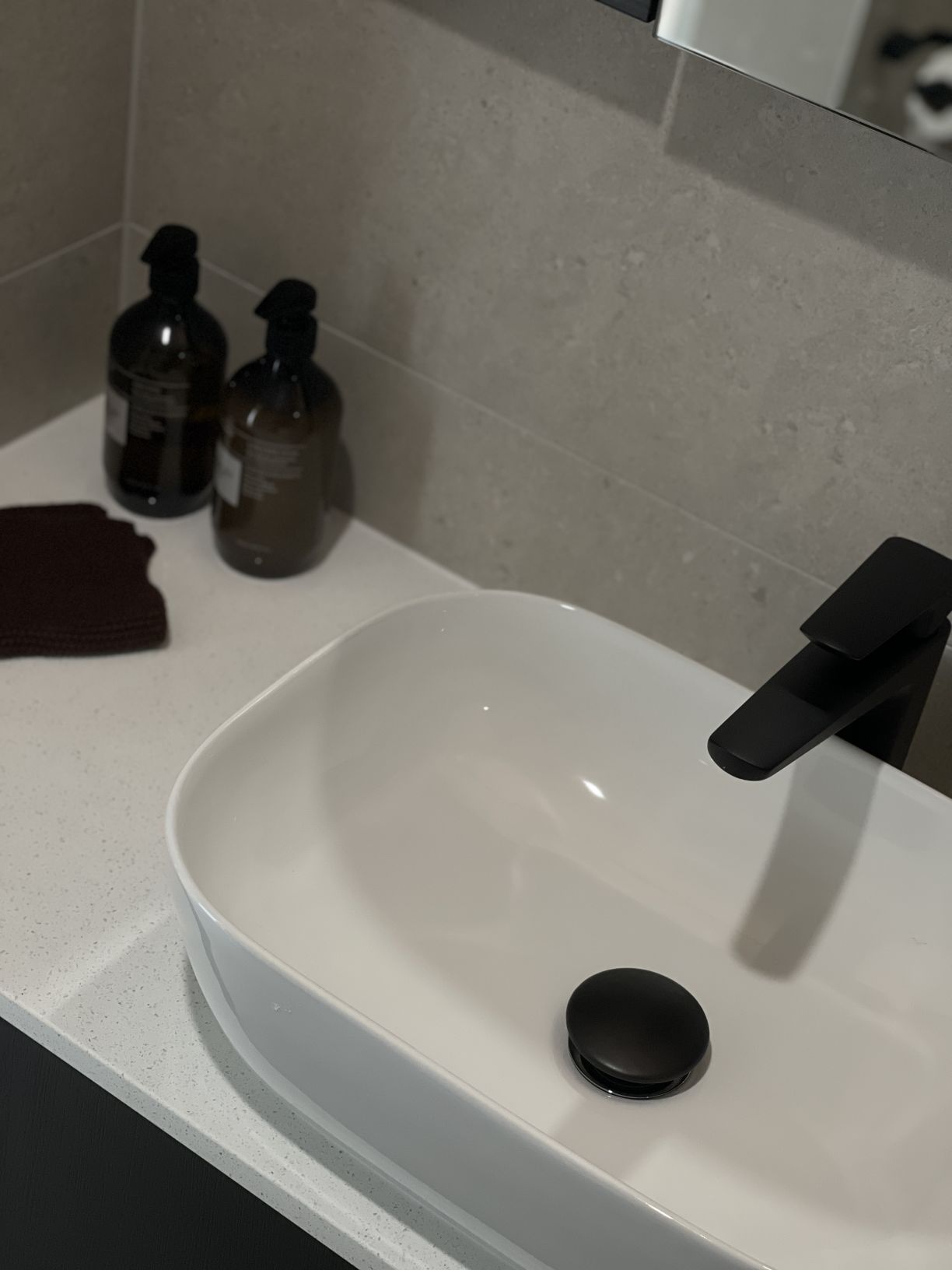 Matte black basin mixer tap and matching pop-up waste installed on a white countertop vessel basin by Level Plumbing Howick.