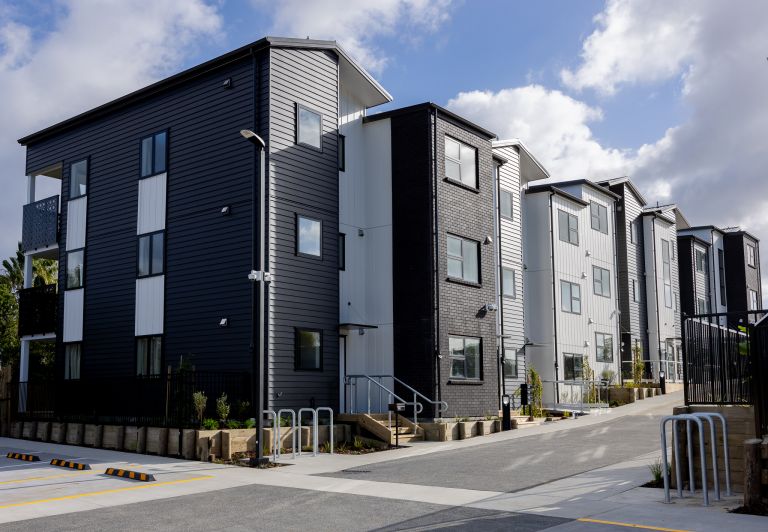 A modern multi-story townhouse development featuring black brick, dark grey weatherboard, and white vertical cladding, representing large-scale residential roofing, drainage, and plumbing installation projects completed by the team at Level Plumbing Howic