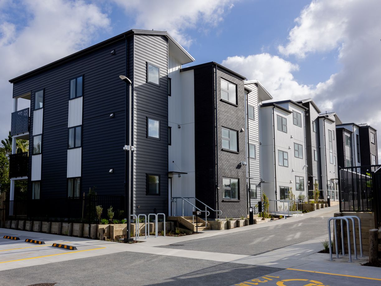 A modern multi-story townhouse development featuring black brick, dark grey weatherboard, and white vertical cladding, representing large-scale residential roofing, drainage, and plumbing installation projects completed by the team at Level Plumbing Howic