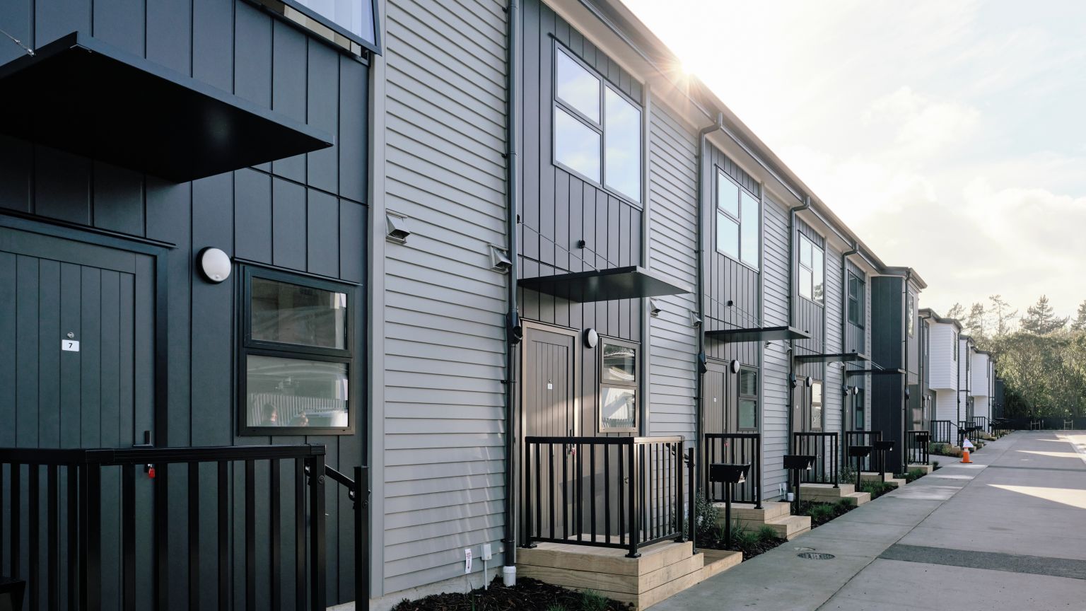 Exterior view of a modern multi-unit townhouse row with downpipes and spouting installation by Level Plumbing