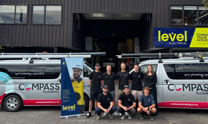 Compass Plumbing team with branded vans outside premises in Morningside celebrating joining Level Group New Zealand as Level Plumbing Morningside
