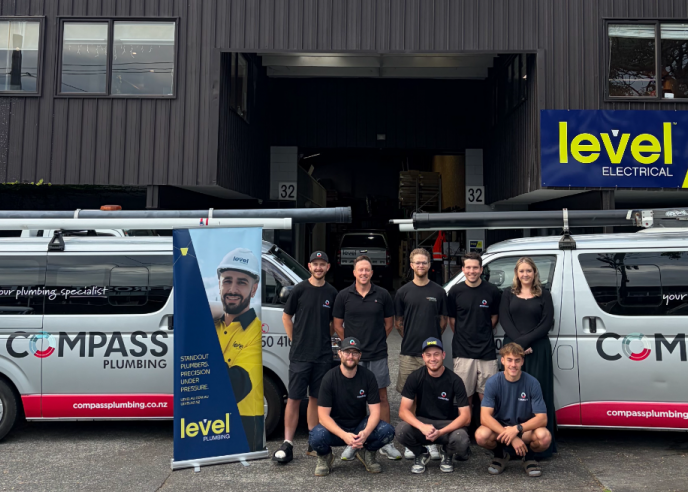 Compass Plumbing team with branded vans outside premises in Morningside celebrating joining Level Group New Zealand as Level Plumbing Morningside
