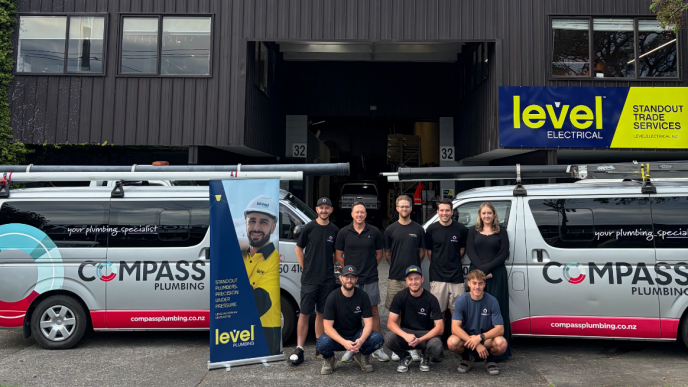Compass Plumbing team with branded vans outside premises in Morningside celebrating joining Level Group New Zealand as Level Plumbing Morningside
