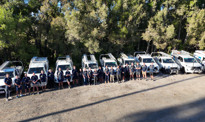 The Bones Plumbing & Roofing team standing in front of their branded vehicles on the Sunshine Coast.