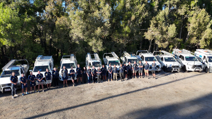 The Bones Plumbing & Roofing team standing in front of their branded vehicles on the Sunshine Coast.